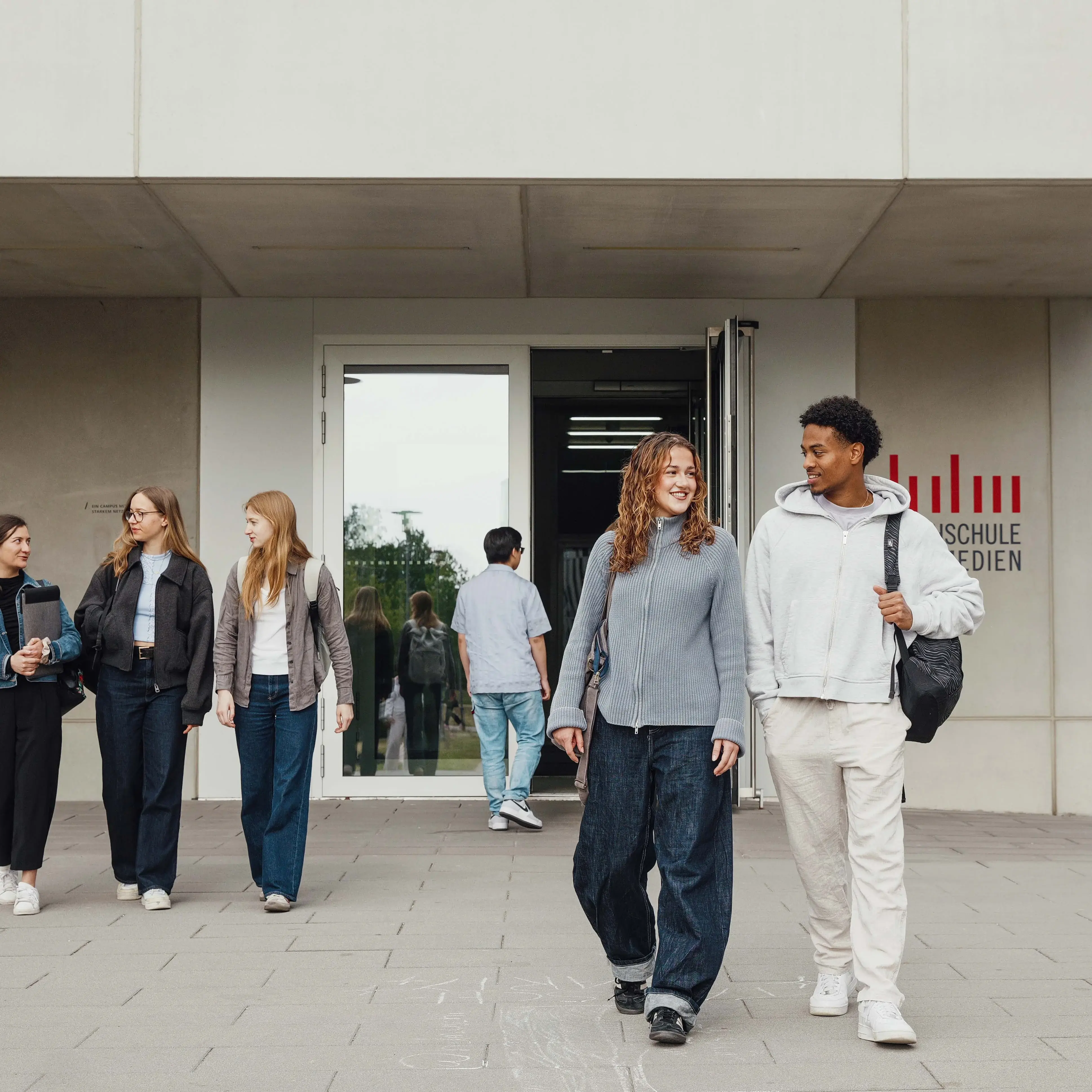 Studierende unterhalten sich beim Verlassen der Hochschule der Medien.